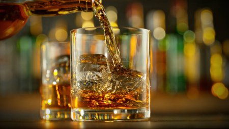 Téléchargez les photos : Detail of pouring whiskey into glass with ice cubes. Super clear ice inside the glass. - en image libre de droit