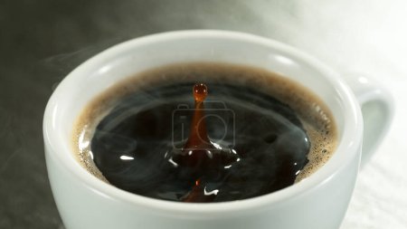 Téléchargez les photos : Détail de la goutte de café tombant dans une tasse de café. Macro shot de café noir chaud boisson. - en image libre de droit
