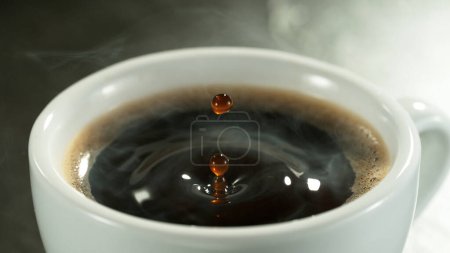 Foto de Detalle de la gota de café cayendo en taza de café. Macro disparo de bebida de café caliente negro. - Imagen libre de derechos