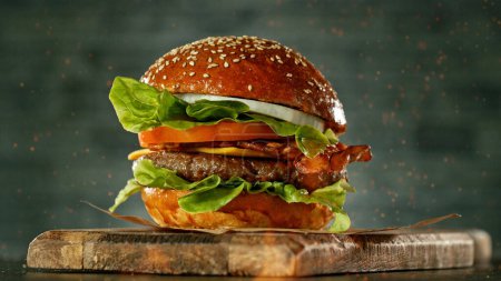 Foto de Deliciosa hamburguesa fresca con queso y fondo gris antiguo. Cocina americana fresca. Llamas en primer plano. - Imagen libre de derechos