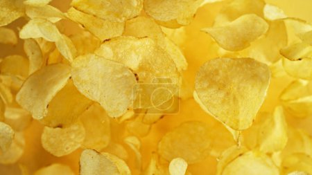 Photo for Potatoes chips flying up in the air. Fly junk food isolated on yellow background. - Royalty Free Image
