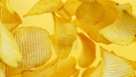 Photo for Potatoes chips flying up in the air. Fly junk food isolated on yellow background. - Royalty Free Image