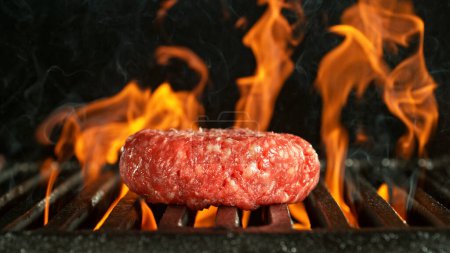 Téléchargez les photos : Barbecue Grill WIth Raw Beef Steak. Barbecue grille de feu sur fond noir. - en image libre de droit