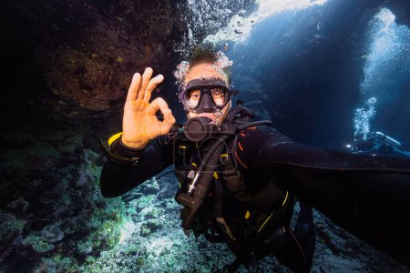 Photo for Male scuba diver gives OK sign in coral cave, Red sea, Egypt. - Royalty Free Image