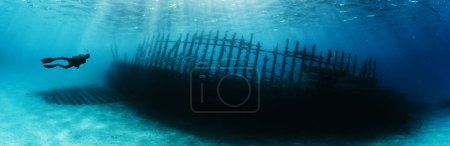 Téléchargez les photos : Silhouette de plongeur explorant le bateau wrack. Activités sportives et récréatives sous-marines. - en image libre de droit