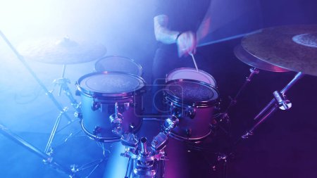 Photo for Drummer Playing on Drums Assembly. Dramatic Scene with Colored Neon Lights. Concert and Performance Theme. - Royalty Free Image