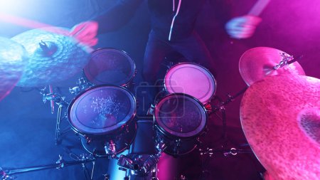 Schlagzeuger spielt auf Drums Assembly. Dramatische Szene mit farbigen Neonlichtern. Thema Konzert und Performance.