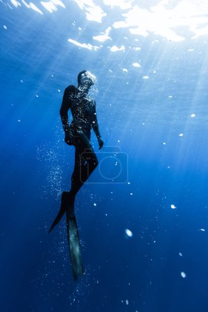 Téléchargez les photos : Plongeur nageant en haute mer avec les rayons du soleil. Jeune homme plongeur déplorant la vie en mer. - en image libre de droit