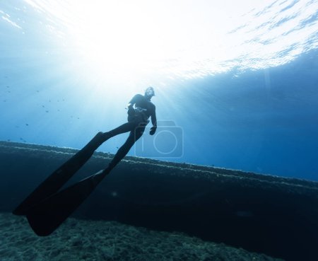 Téléchargez les photos : Freediver Swimming in Deep Sea and Exploring Ship Wreck. Jeune homme plongeur déplorant la vie en mer. - en image libre de droit