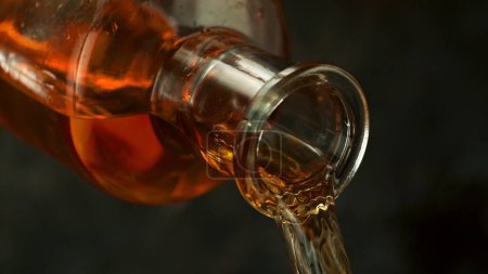 Téléchargez les photos : Bouteille de whisky avec du liquide coulant. Détail de bouteille de whisky, boissons Contexte. - en image libre de droit