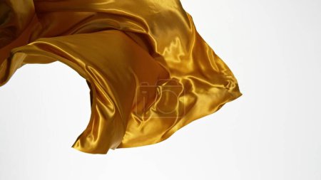 Téléchargez les photos : Élégant tissu de satin doré lisse séparé sur fond blanc. Texture du tissu volant, mouvement de gel. - en image libre de droit