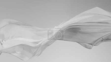 Téléchargez les photos : Tissu transparent blanc élégant et lisse séparé sur fond gris. Texture du tissu volant en mouvement de gel. - en image libre de droit
