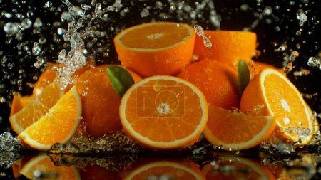 Foto de Montón de naranjas con salpicaduras de agua alrededor. Aislado sobre fondo negro. - Imagen libre de derechos