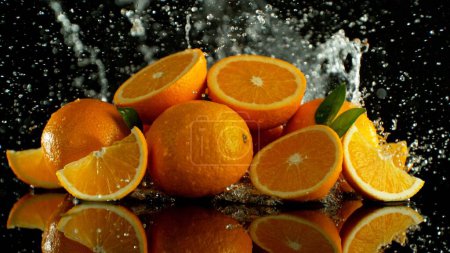 Téléchargez les photos : Pile d'oranges avec éclaboussures d'eau autour. Isolé sur fond noir. - en image libre de droit