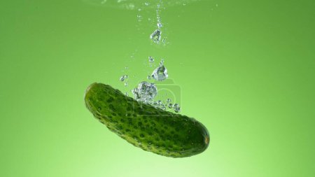 Téléchargez les photos : Mouvement de gel du concombre cru frais sous l'eau, isolé sur fond coloré. - en image libre de droit