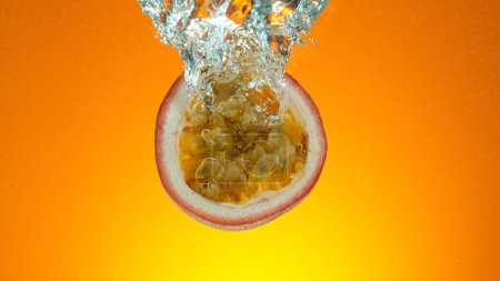 Téléchargez les photos : Tranche de fruit de la passion fraîche sous l'eau, isolée sur fond coloré. - en image libre de droit