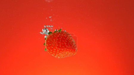 Foto de Congelar el movimiento de fresa fresca bajo el agua, aislado sobre fondo de color. - Imagen libre de derechos