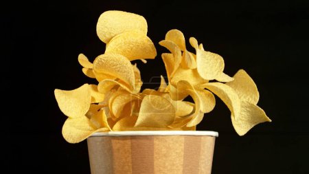 Photo for Flying Fried Potato Chips Exploding from Paper Bucket. Concept of Flying Junk Food. - Royalty Free Image