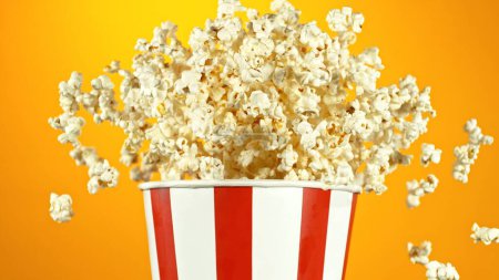 Photo for Popcorn Flying up in the Air from Paper Bucket. Isolated on Golden Background. - Royalty Free Image