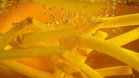 Foto de Freeze Motion of French Fries Floating in Cooking Oil. Comida chatarra, Fondo de comida rápida. - Imagen libre de derechos