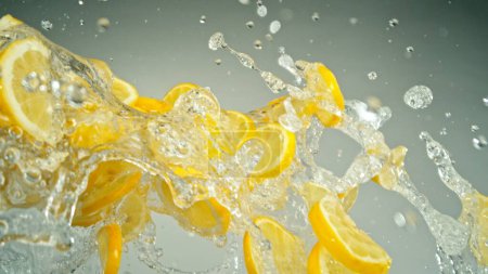 Photo for Freeze Motion of Flying Slices of Lemons with Splashing Water. Isolated on Grey Background, closeup. - Royalty Free Image