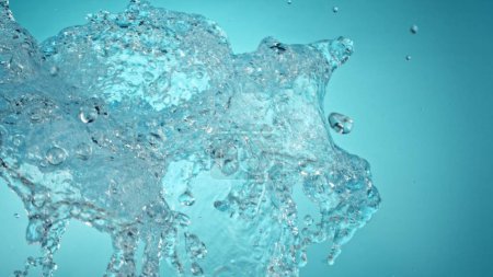 Foto de Congelar movimiento de agua salpicadura en primer plano. Aislado sobre fondo azul. - Imagen libre de derechos