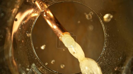 Foto de Macro Shot de cerveza vertiendo en el vidrio del grifo. Ángulo de perspectiva único desde el fondo de un vaso. Congelar movimiento. - Imagen libre de derechos