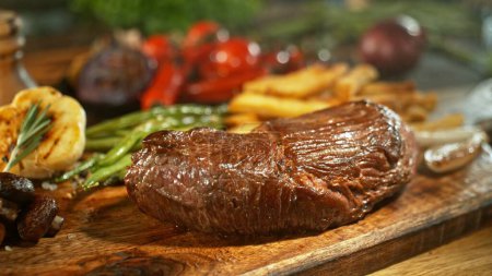 Téléchargez les photos : Steak de boeuf prêt à manger, servi sur une table en bois. Délicieuse viande avec légumes et frites sur fond. - en image libre de droit