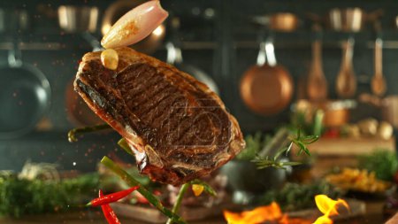 Téléchargez les photos : Savoureux steak de boeuf volant dans les airs. Cuisine avec ustensiles sur fond. Concept de nourriture volante. - en image libre de droit