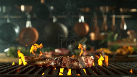 Téléchargez les photos : Steak de boeuf savoureux placé sur la grille de gril. Cuisine avec ustensiles sur fond. Concept de préparation des aliments. - en image libre de droit