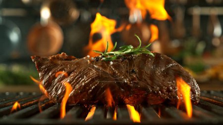 Téléchargez les photos : Steak de boeuf savoureux placé sur la grille de gril. Cuisine avec ustensiles sur fond. Concept de préparation des aliments. - en image libre de droit