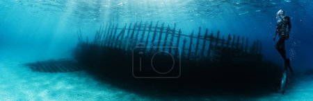 Téléchargez les photos : Silhouette de plongeur libre explorant le bateau wrack. Activités sportives et récréatives sous-marines. - en image libre de droit