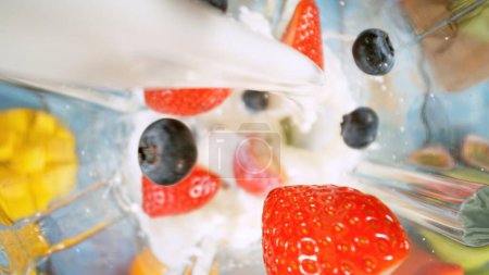 Téléchargez les photos : Tir aérien de morceaux de fruits avec du lait dans le mélangeur. Préparation de boisson Smoothie, vue sur le dessus Composition. - en image libre de droit