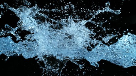 Foto de Salpicaduras de agua volando en el aire sobre fondo negro. Congelar el movimiento de salpicaduras de agua realistas. - Imagen libre de derechos