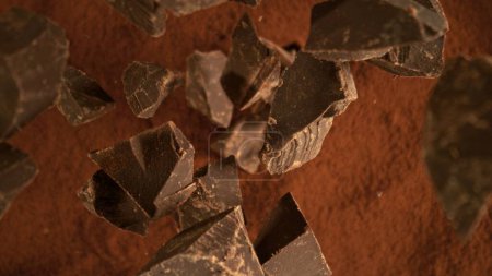 Congelar el movimiento del grupo volador de piezas de chocolate crudo. Caer en polvo de cacao.