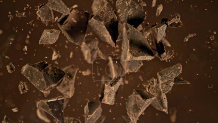 Freeze motion of flying group of raw chocolate pieces, falling into melted chocolate. Chunks are falling down.