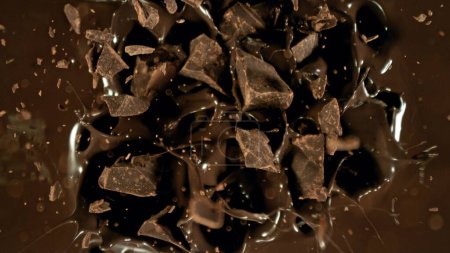 Congelar el movimiento del grupo volador de piezas de chocolate crudo, cayendo en el chocolate derretido. Trozos se están cayendo.