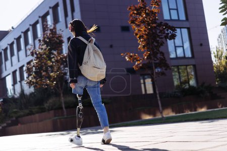 Photo for Young woman student with prosthetic leg walking in university campus. Woman with bionic leg. Woman with leg prosthesis equipment. - Royalty Free Image