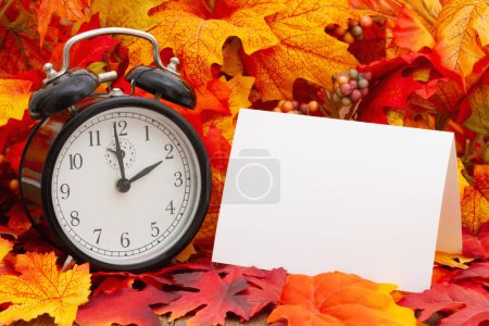 Photo for Blank greeting card with an alarm clock and fall leaves for your time change or autumn time message - Royalty Free Image