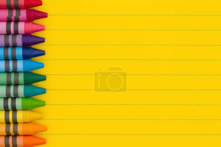Photo for Bright yellow ruled line notebook paper with crayons background for you education or school message - Royalty Free Image