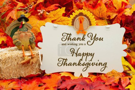 Happy Thanksgiving sign with a turkey on a bale of hay and fall leaves-stock-photo