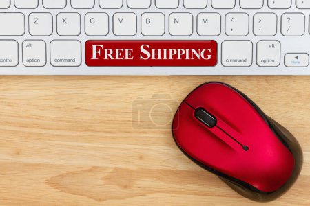 Foto de Mensaje de envío gratuito con el ratón rojo y un teclado en un escritorio de madera para su mensaje de compra en línea - Imagen libre de derechos