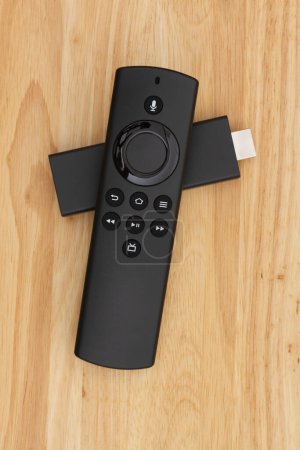 Téléchargez les photos : Lecteur TV noir à distance avec dispositif de streaming HDMI sur un bureau en bois pour votre couper le message du câble - en image libre de droit