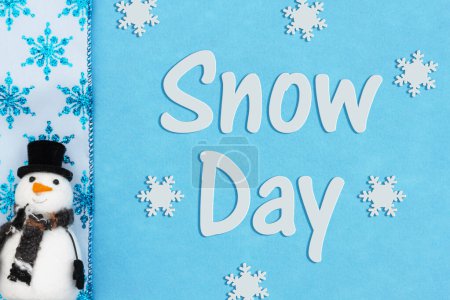 Téléchargez les photos : Message du jour de neige avec un bonhomme de neige et des flocons de neige bleus sur bleu - en image libre de droit