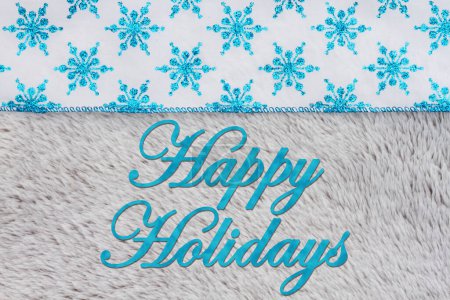 Téléchargez les photos : Joyeuses fêtes de vœux avec des flocons de neige bleus sur un matériau en peluche gris - en image libre de droit