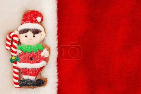 Téléchargez les photos : Joli elfe en pain d'épice sur fond de vacances en peluche rouge pour votre message d'hiver ou de saison - en image libre de droit