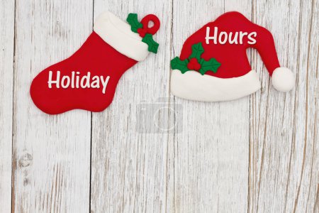 Téléchargez les photos : Heures de vacances message avec chapeau de Père Noël et bas de Noël sur bois altéré avec de l'espace pour vos heures d'ouverture de Noël - en image libre de droit