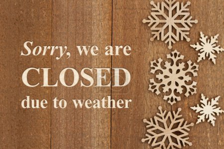 Téléchargez les photos : Désolé, nous sommes fermés en raison de la météo signe avec des flocons de neige en bois sur bois altéré - en image libre de droit