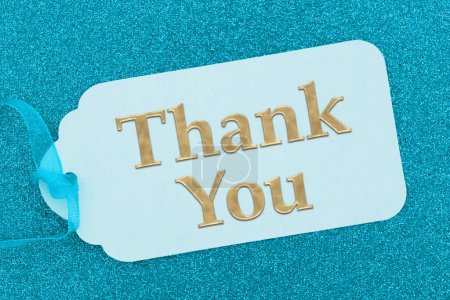 Thank you message on a teal gift tag on glitter paper with a ribbon
