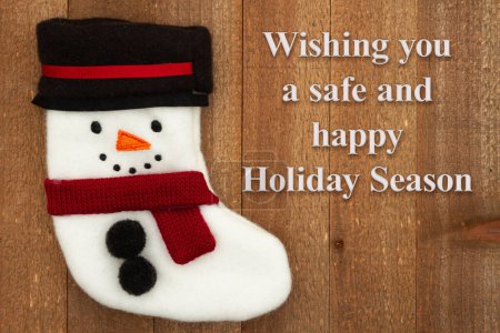 Photo for Wishing you a safe and happy Holiday Season with a snowman stocking on weathered wood - Royalty Free Image